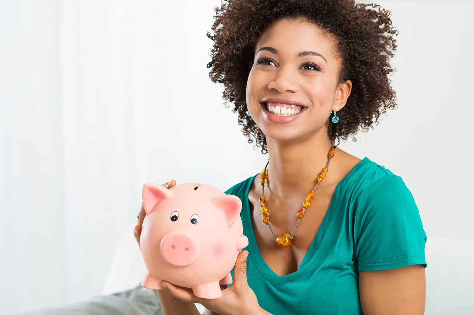 Happy Young Woman Saves Money in Piggy bank