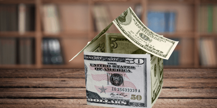 house made of dollars on wooden table