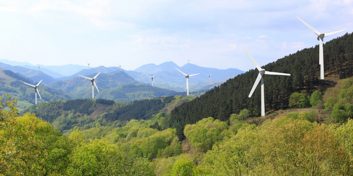 More wind turbines in the mountains on the horizon line on cloudy sky background